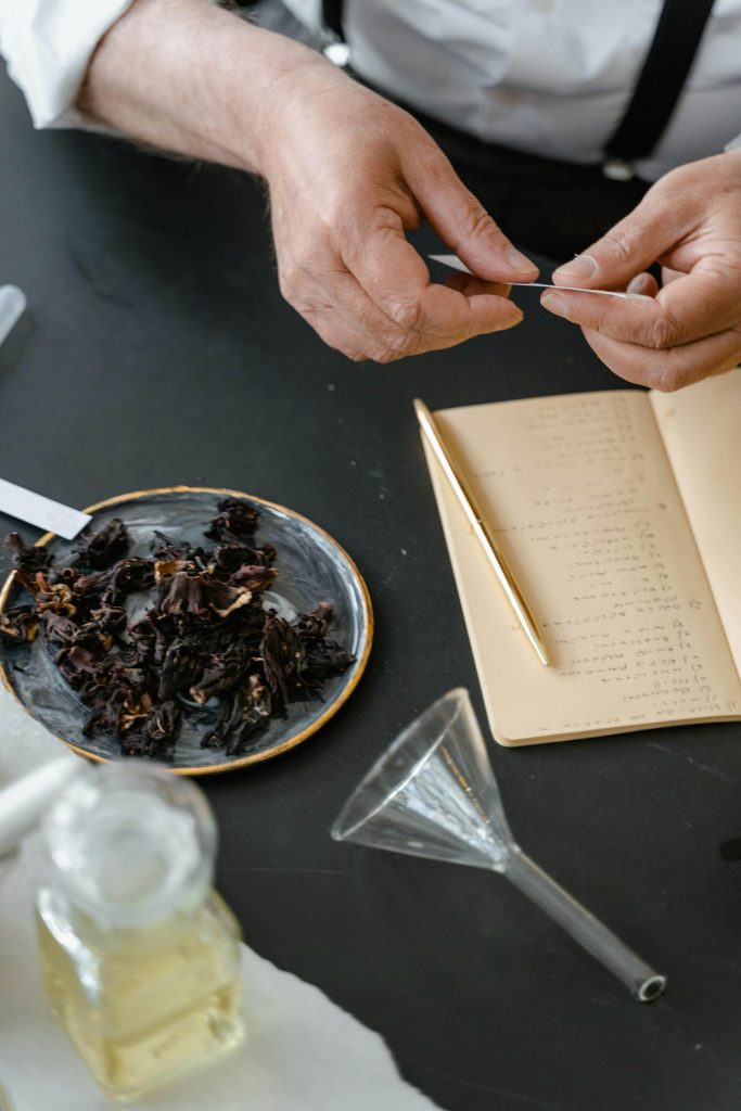 Persona tomando notas con flores secas en una mesa